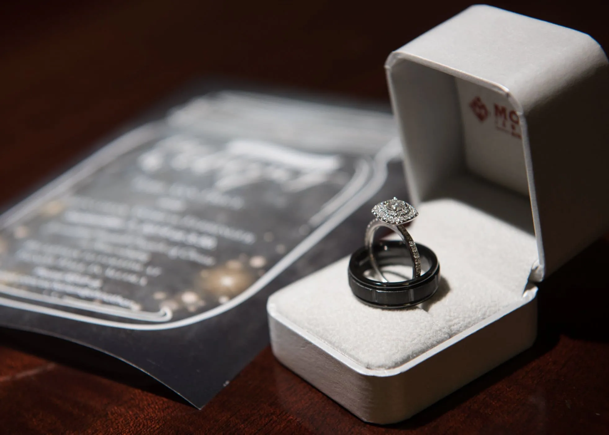 Wedding rings in a ring box beside a wedding invitation